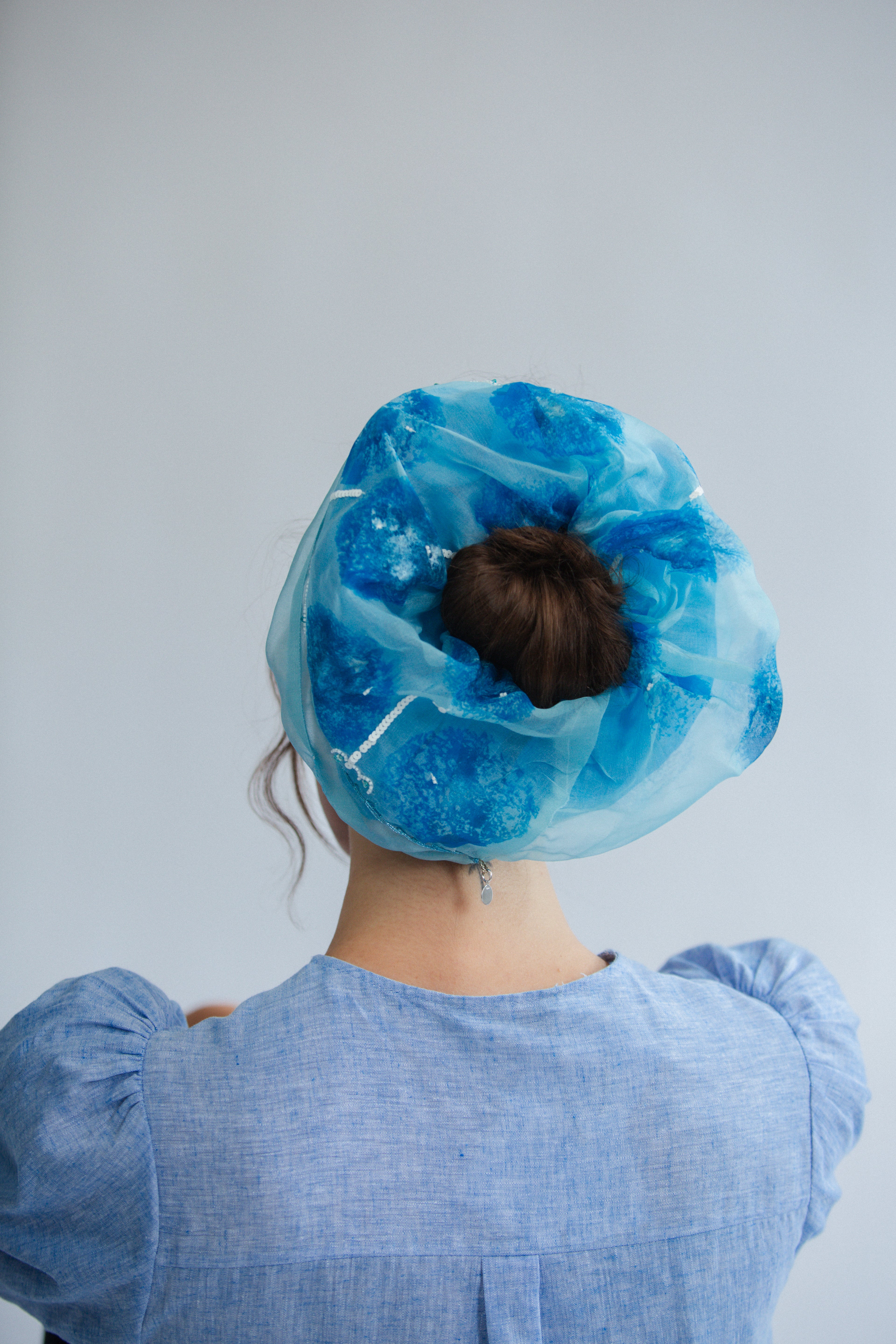 Model wearing a blue scrunchy against a plain background