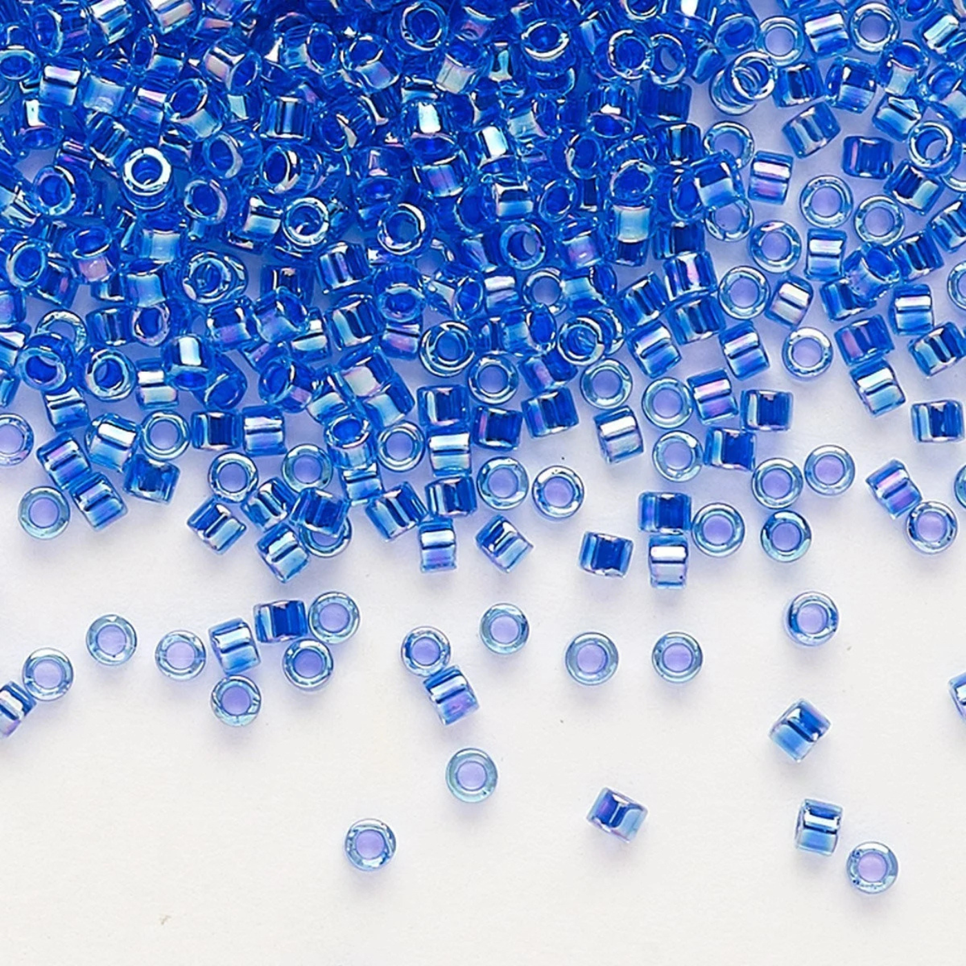 Blue Miyuki glass beads scattered on a white background