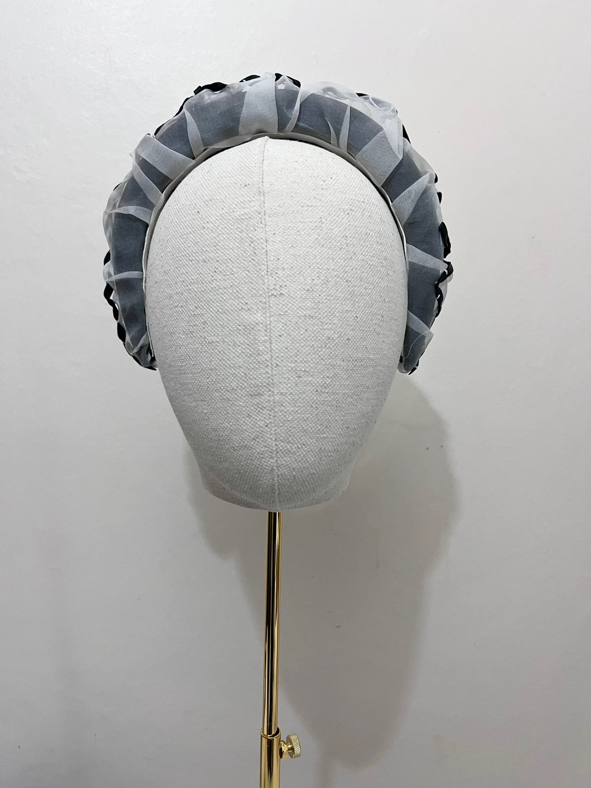 Gray headband with geometric pattern on a mannequin head against a white background