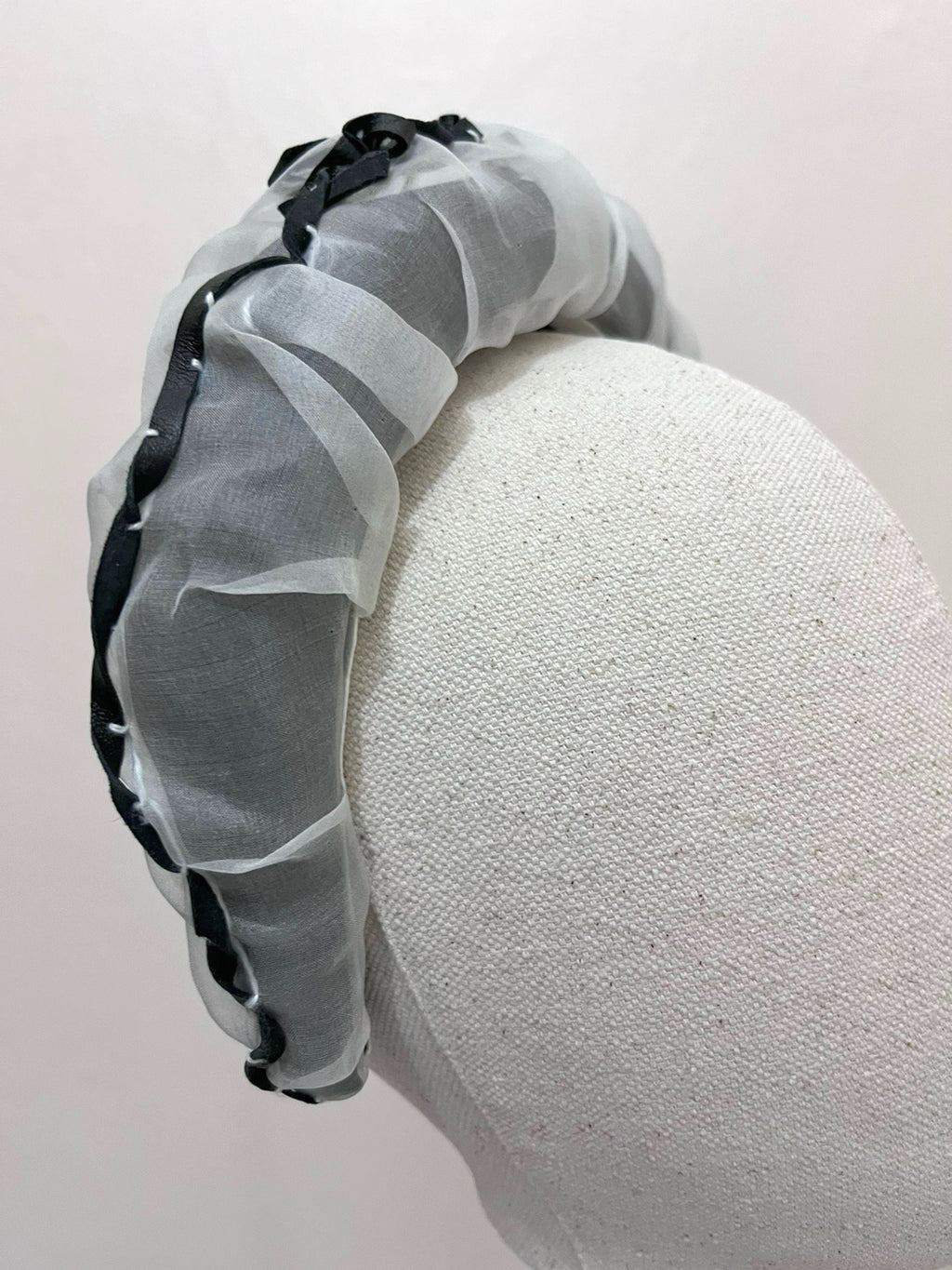Gray headband with black accents on a white foam block