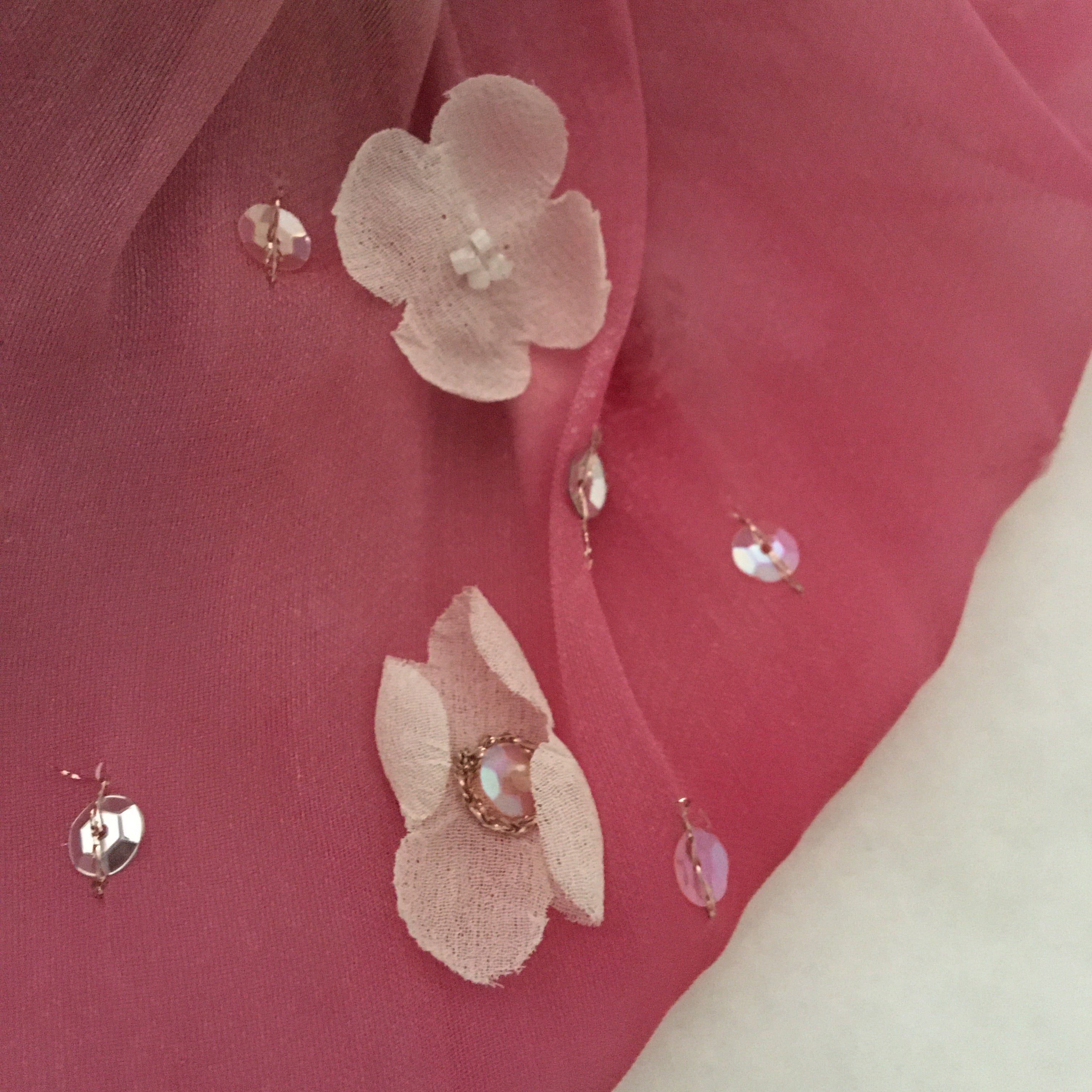 Pink fabric with floral embellishments on a white background