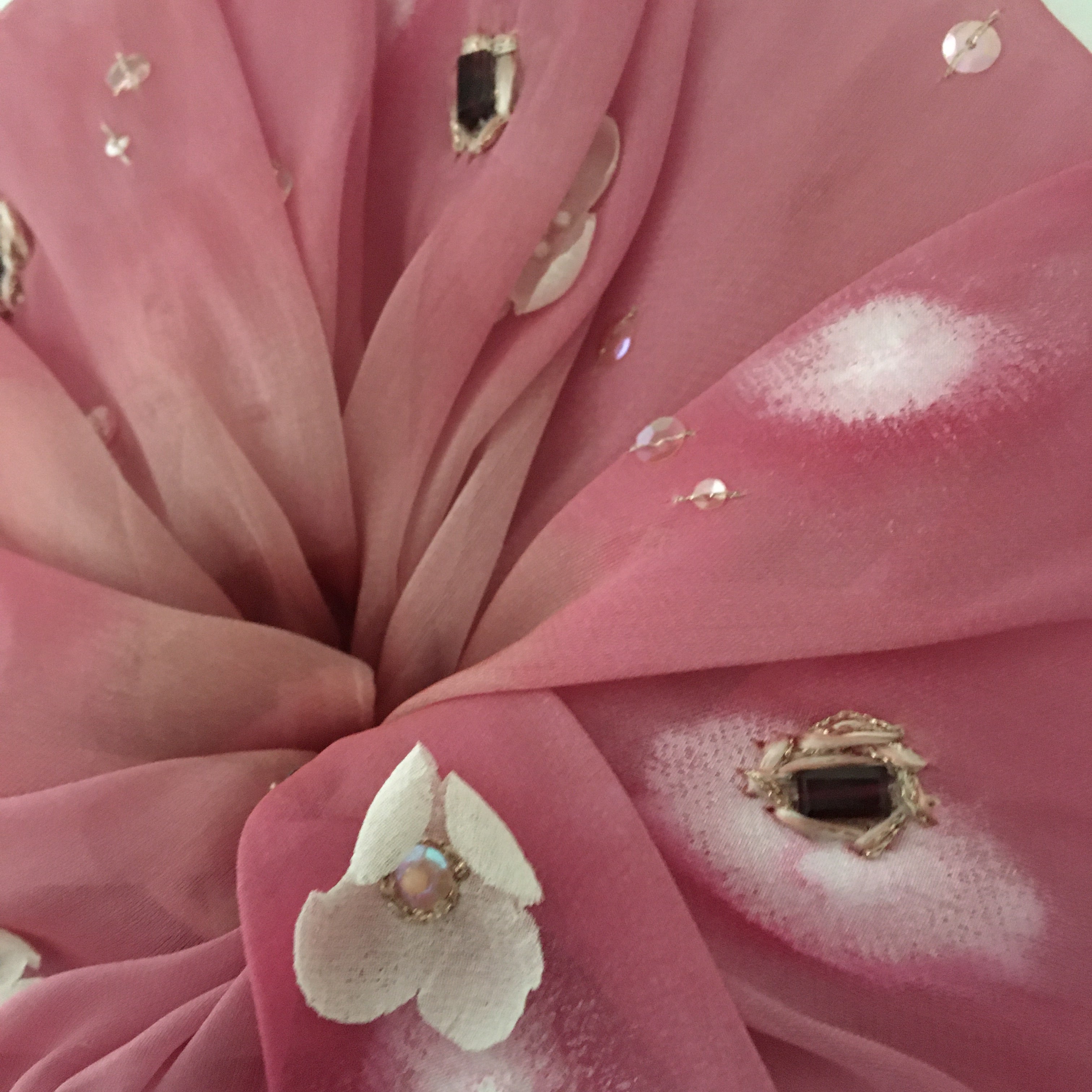 Close-up of pink fabric  adorned with gemstones on a pink background