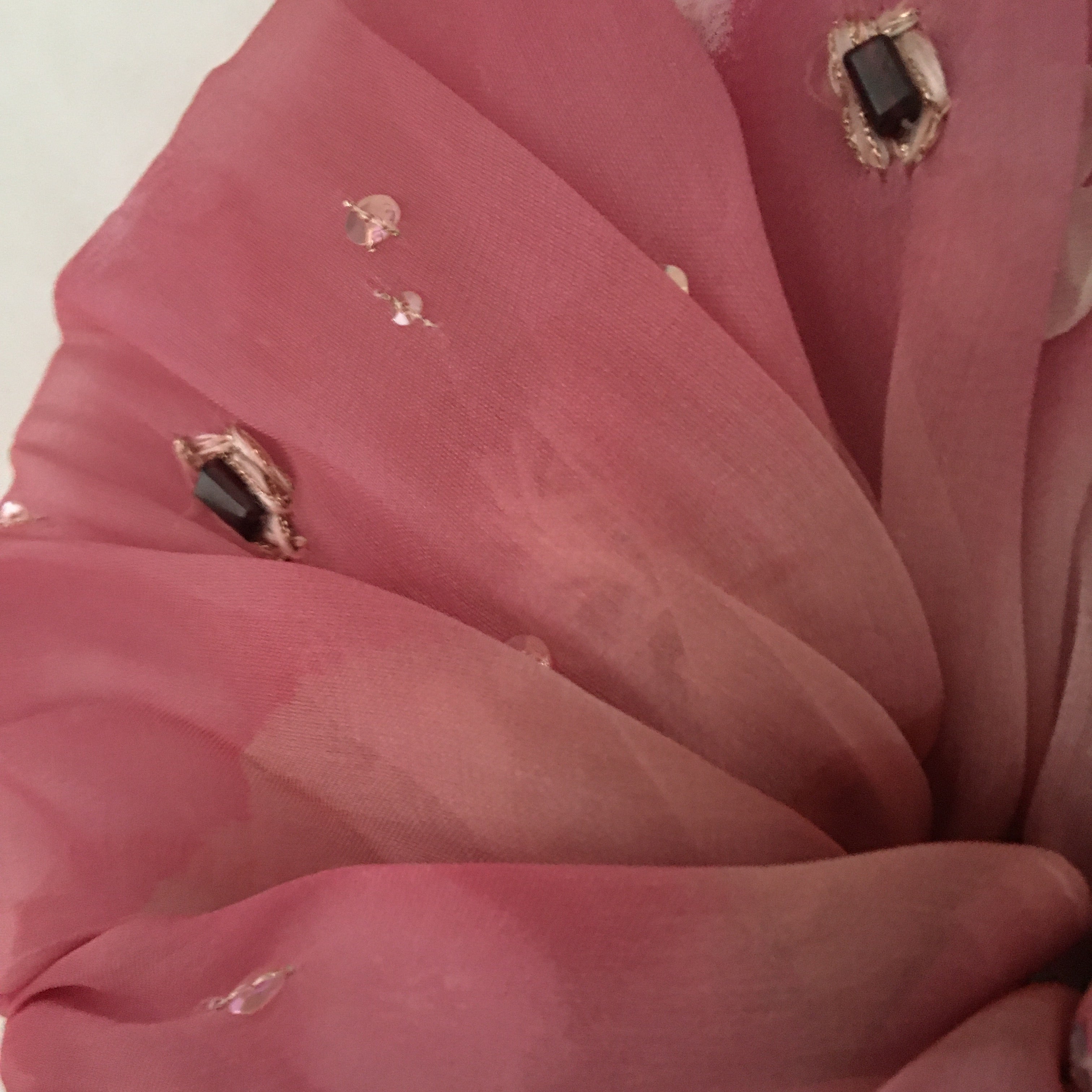 Close-up of a scrunchy with pink fabric and gemstones on a white background