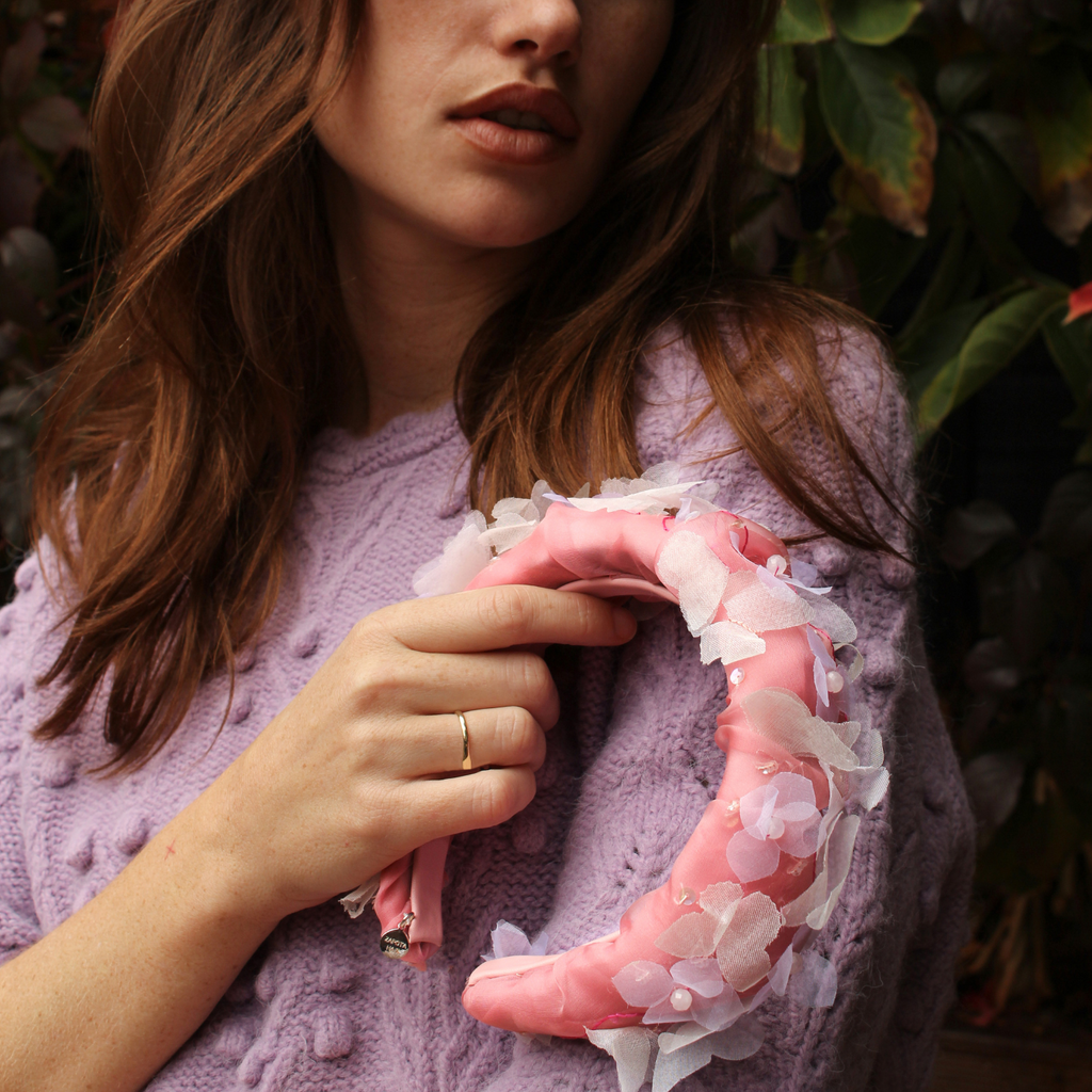 Person holding a pink boot with floral details against a natural background