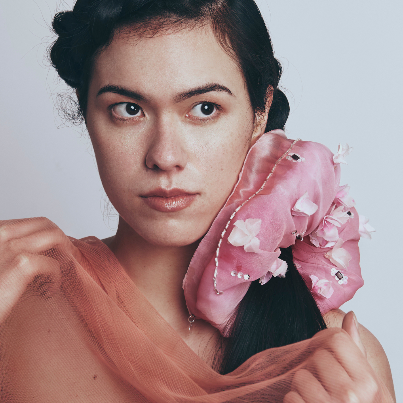 Model wearing a pink floral headscarf and floral scrunchy with a plain background