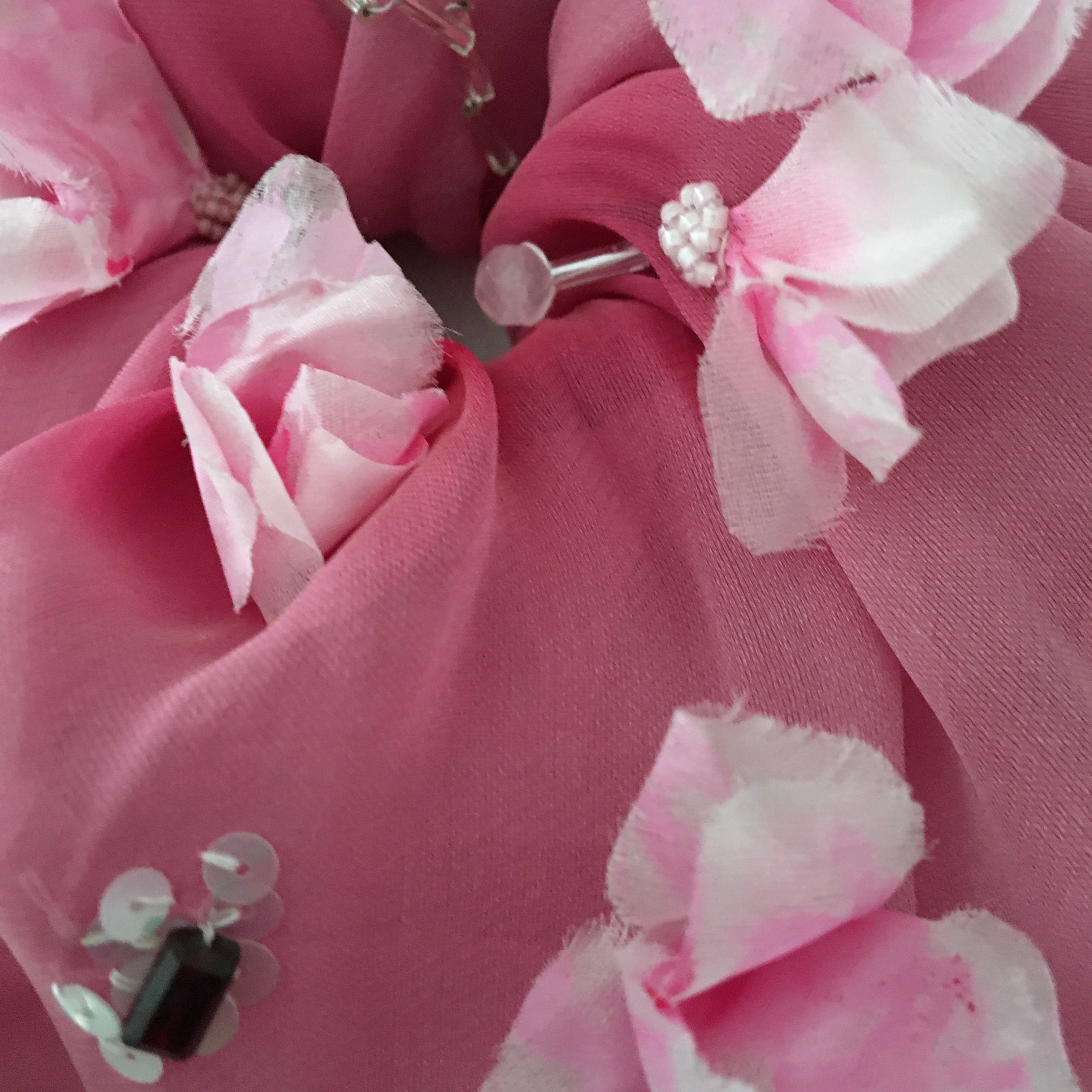 Close-up of a pink fabric flower scrunchy with decorative elements.