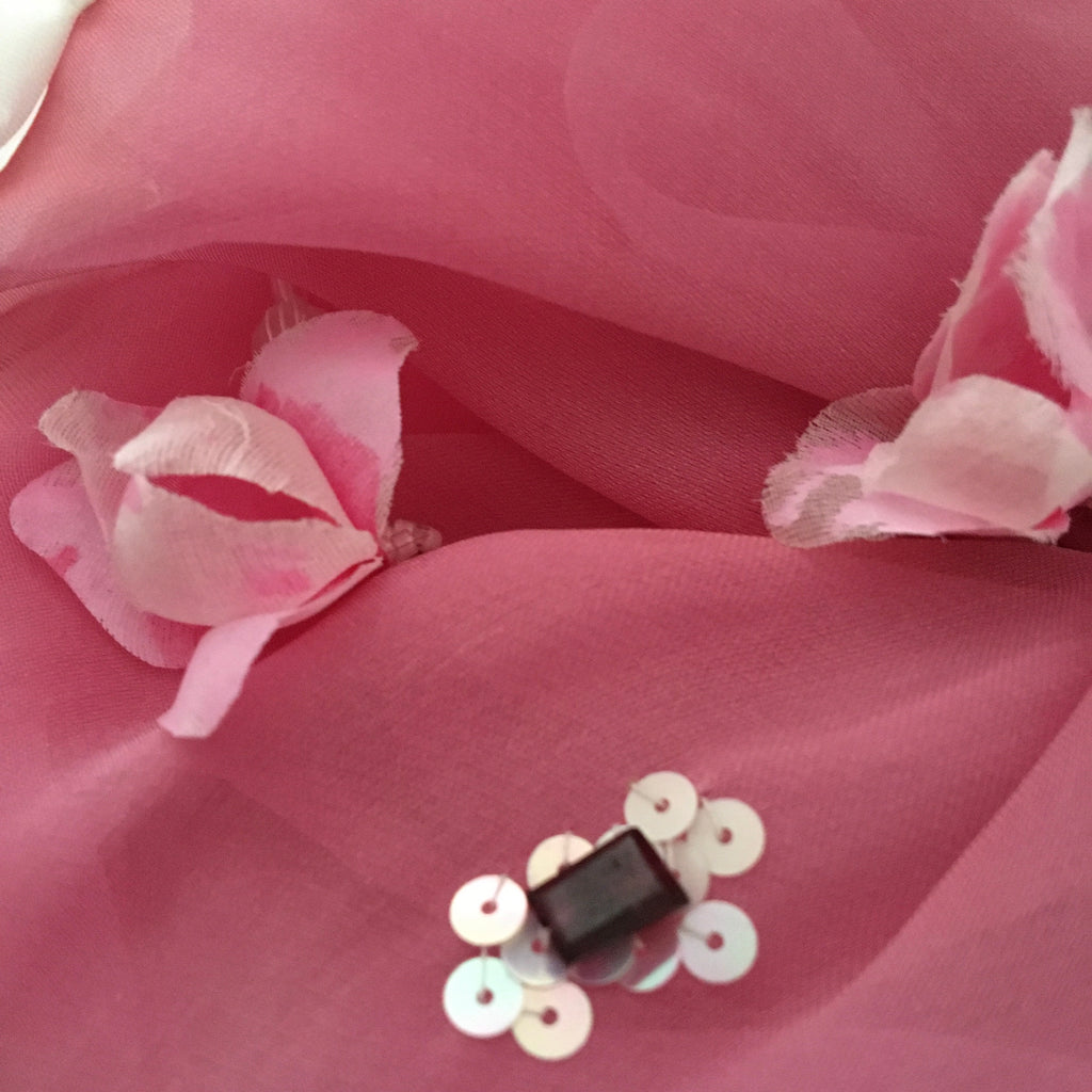 Pink fabric with gemstones, floral elements and sequins on a pink background