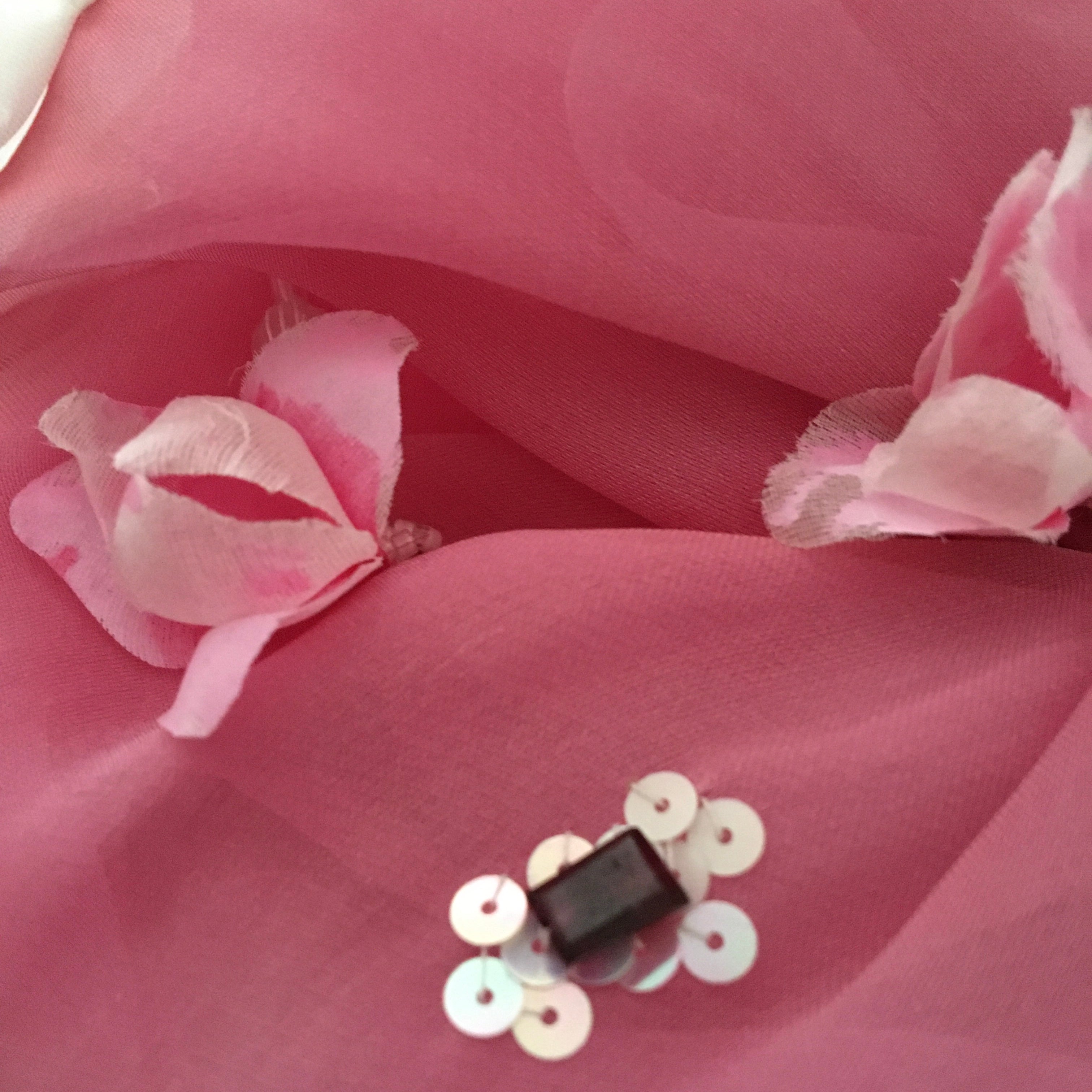 Pink fabric with gemstones, floral elements and sequins on a pink background