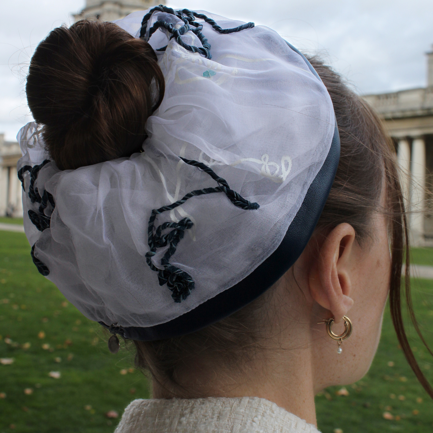Model wearing a white large scrunchy with navy blue embroidery made with leather