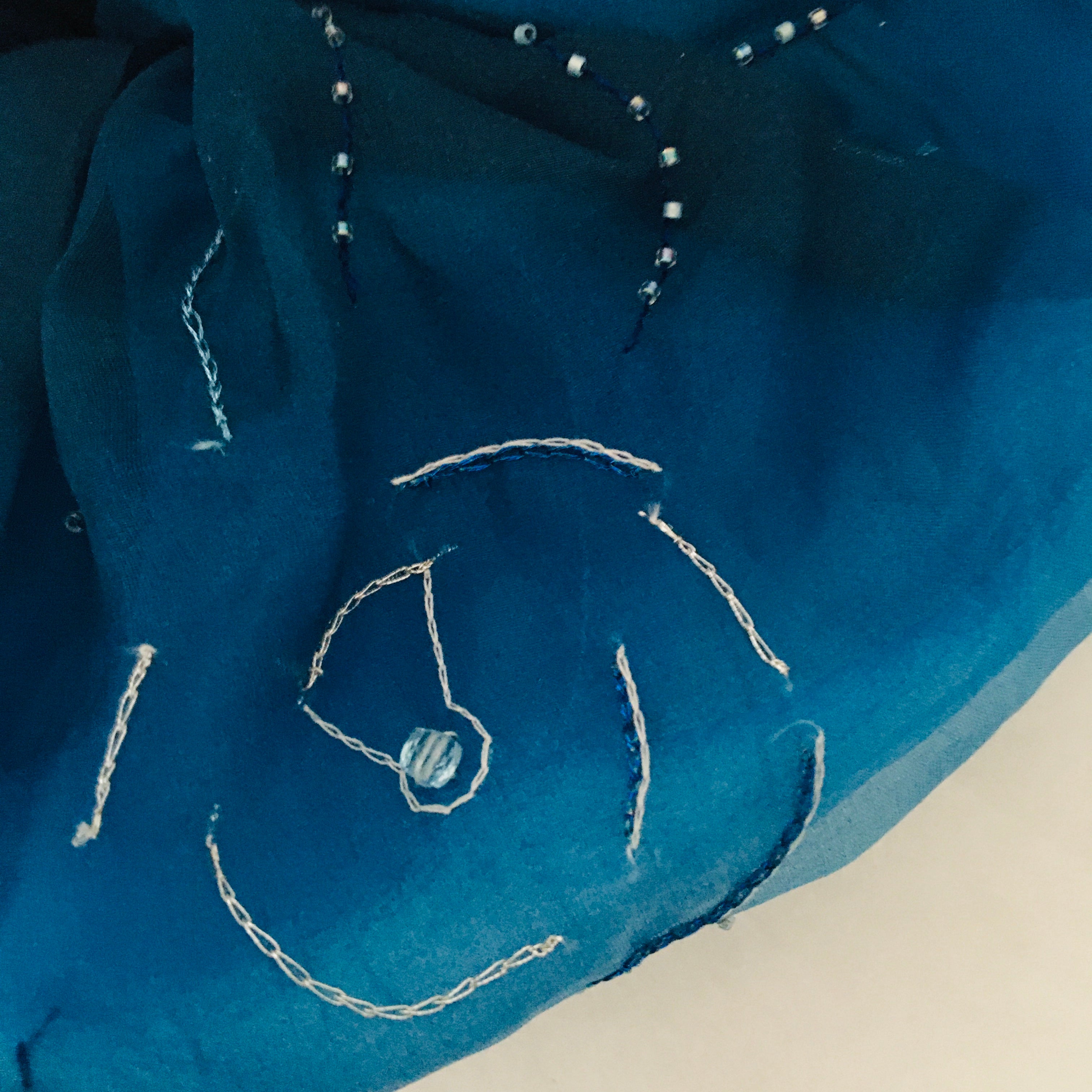 Blue fabric with white embroidered design on a white background