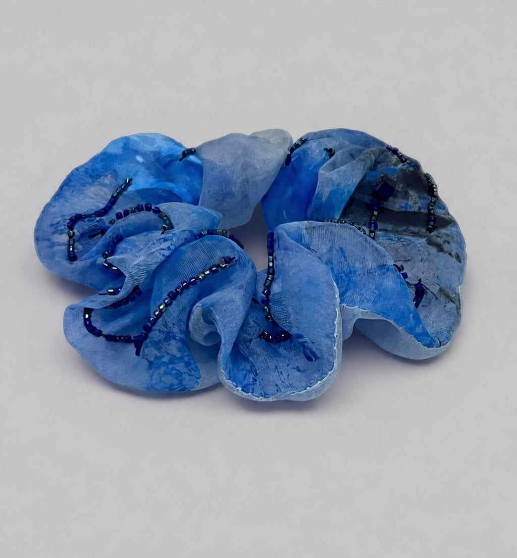 Blue scrunchie with decorative elements on a light gray background