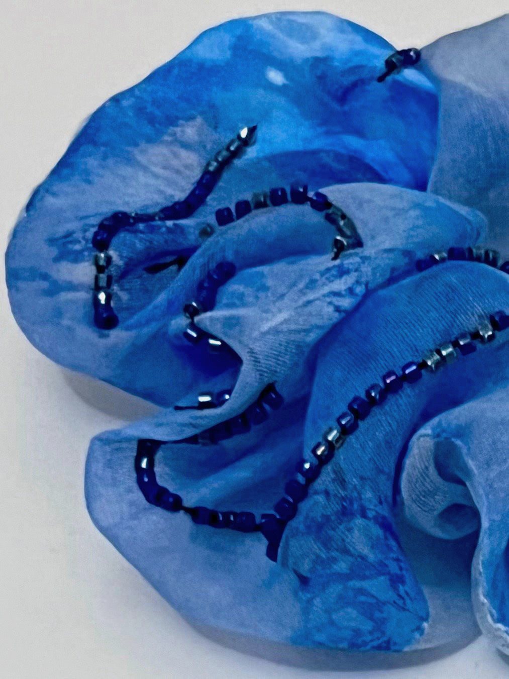 Blue scrunchie with beaded accents on a white background