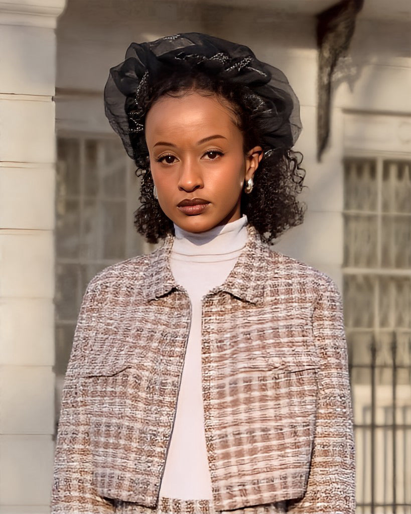 Woman wearing a textured jacket and black headpiece outdoors.