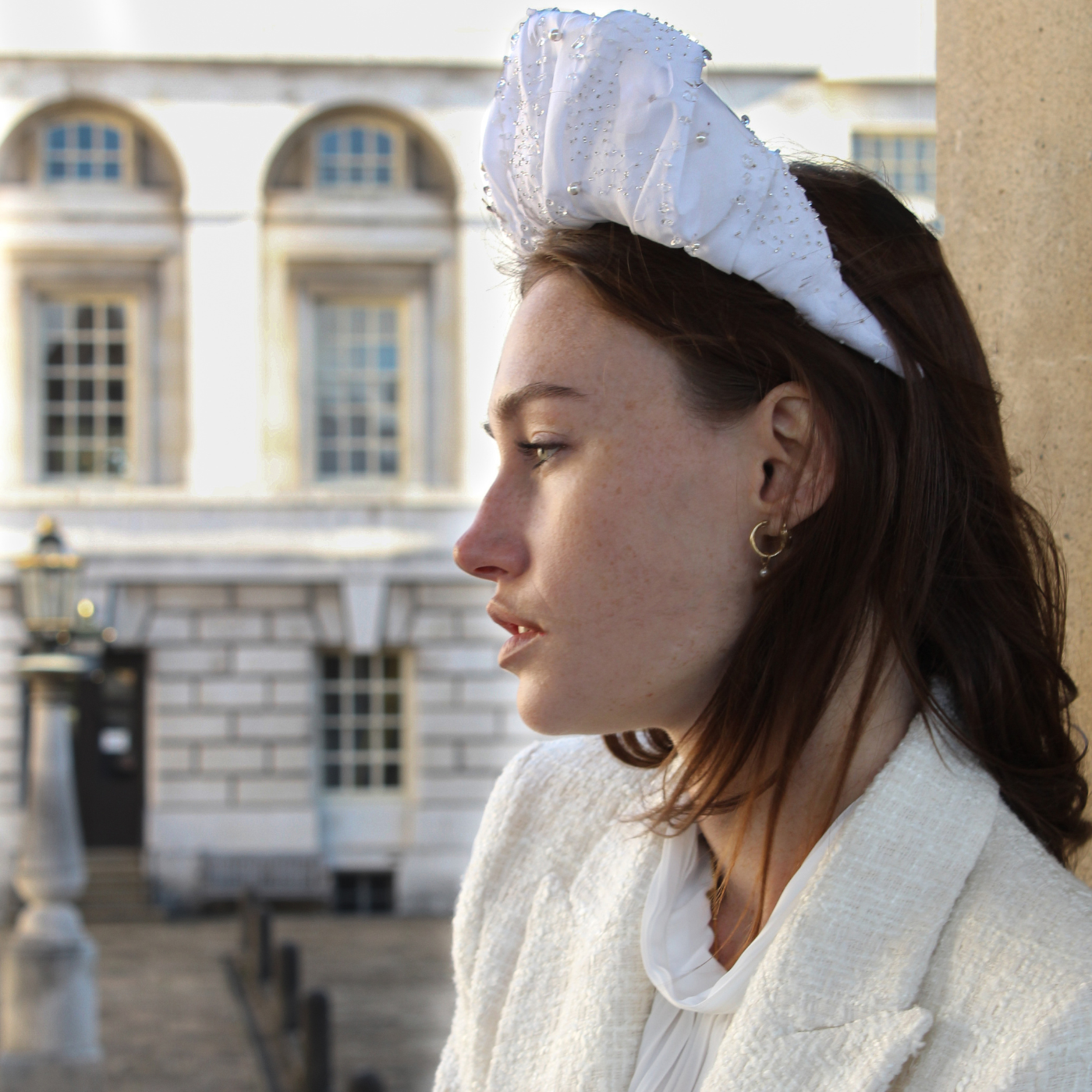 Woman wearing a white headband with a building in the background