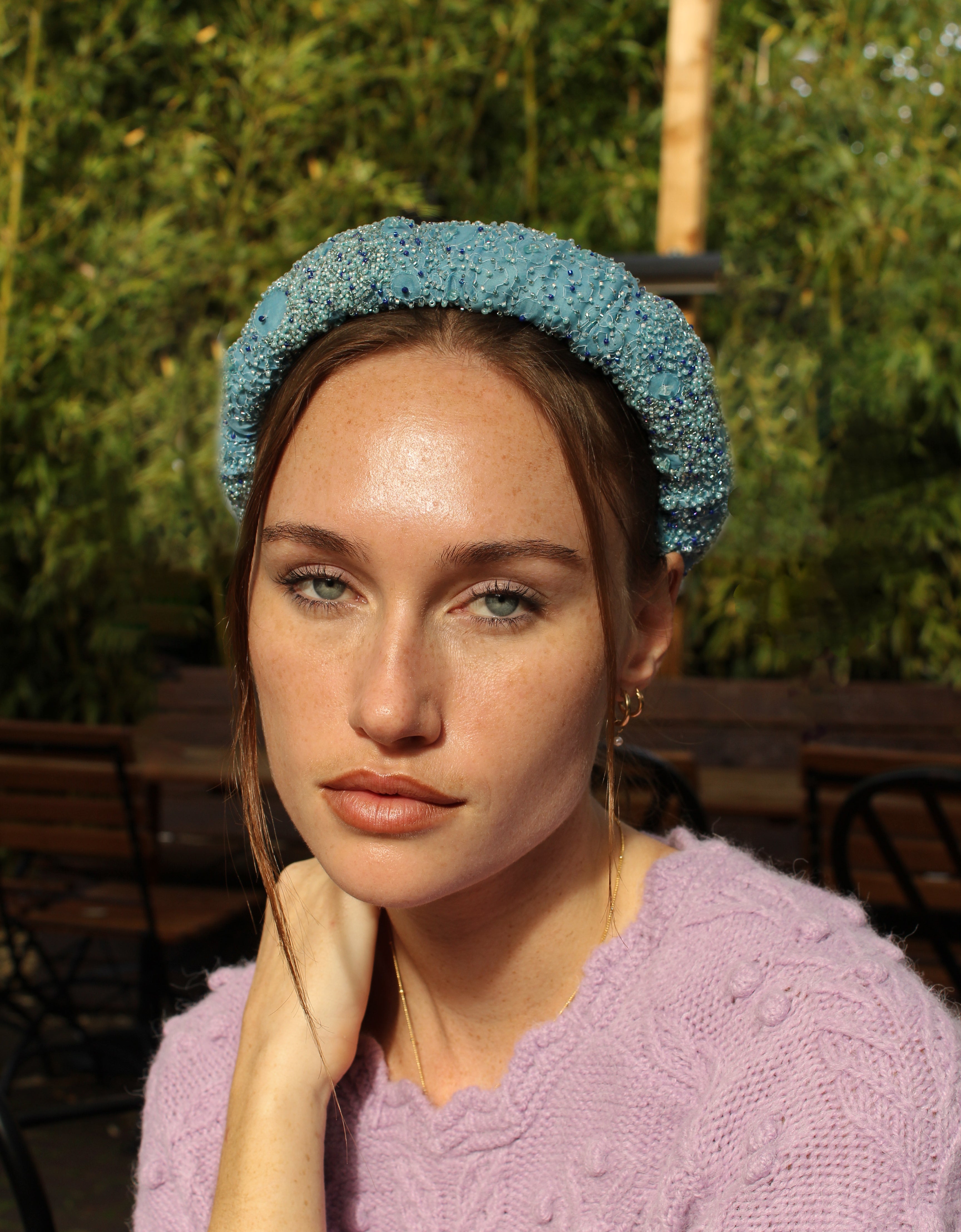 Model wearing a blue headband with a blurred green outdoor background